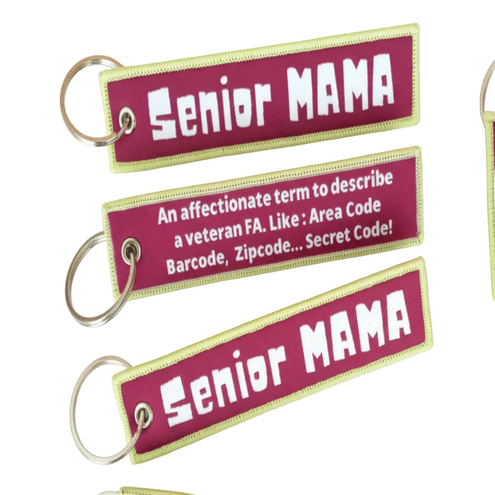 A set of three rectangular luggage tags with yellow and pink text, each with a different phrase related to being a 'Senior Mama'. They are attached to a keychain and displayed against a background with a map.