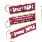 A set of three rectangular luggage tags with yellow and pink text, each with a different phrase related to being a 'Senior Mama'. They are attached to a keychain and displayed against a background with a map.